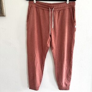 Vuori Performance Joggers in a brick color.
